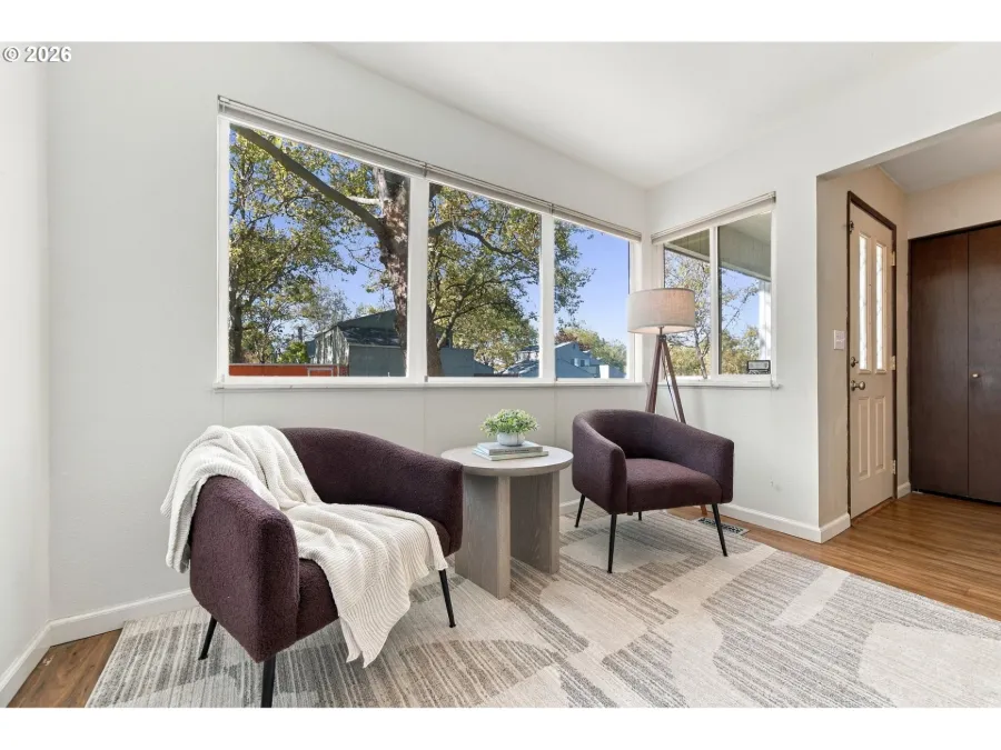 Calm reading corner staged with two plum armchairs, a round side table and a cream throw by a large window
