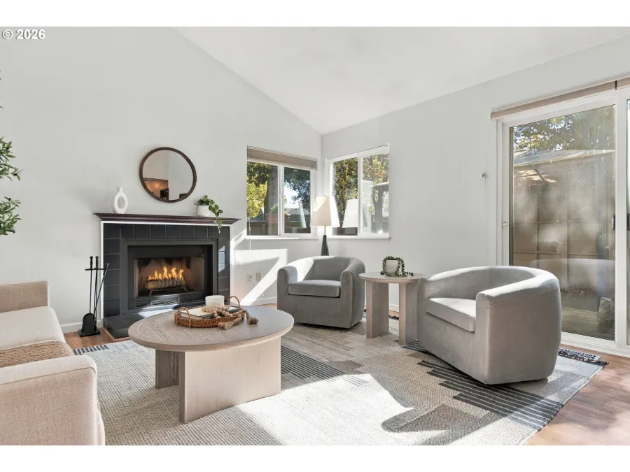 Staged living room with a fireplace, round coffee table and grey swivel chairs