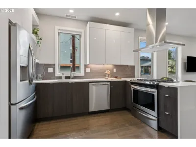 Modern townhome kitchen with dark lower cabinets and stainless appliances